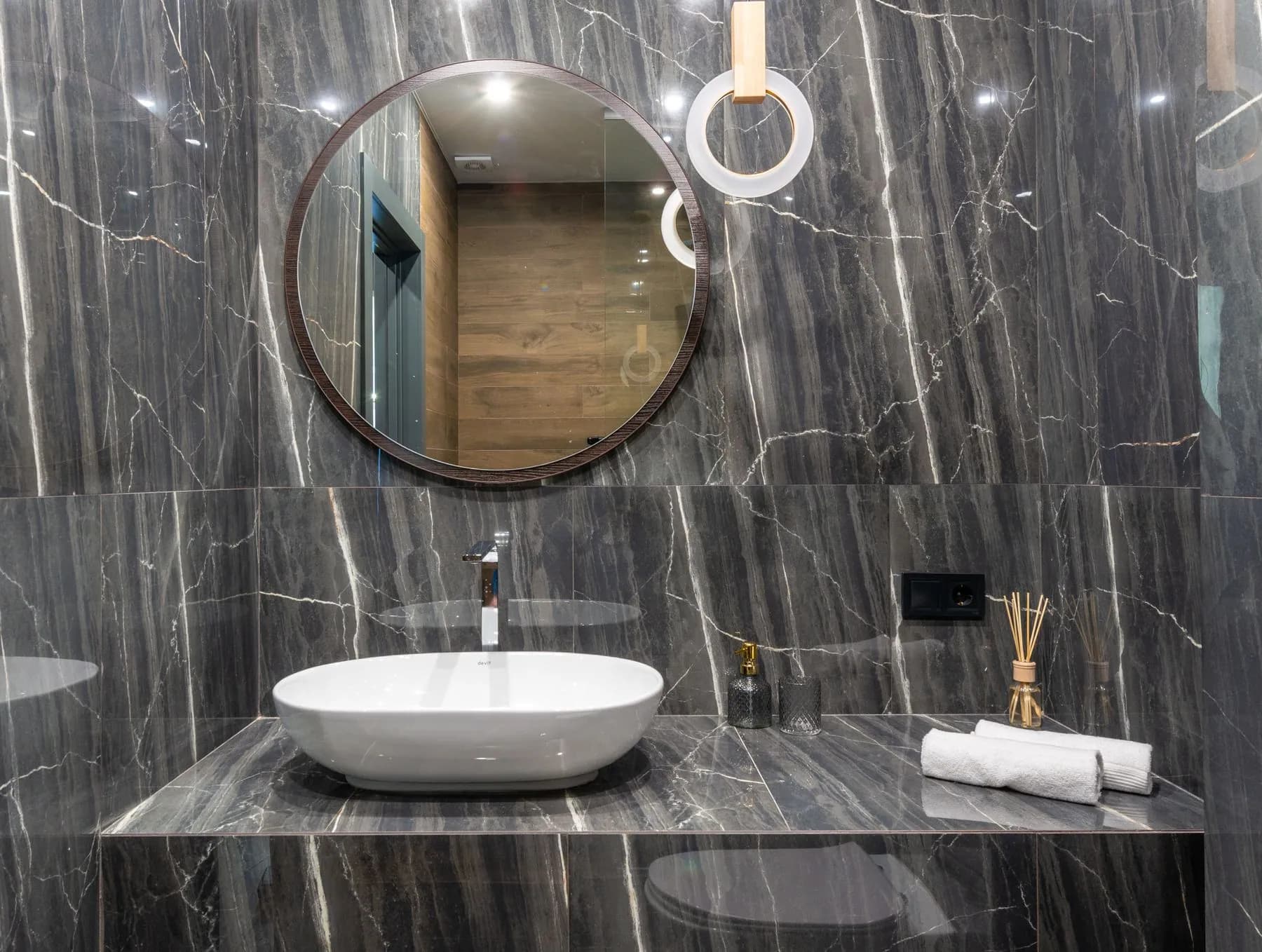 Powder room with a stone shelf vanity and a vessel basin against book-matched marble walls