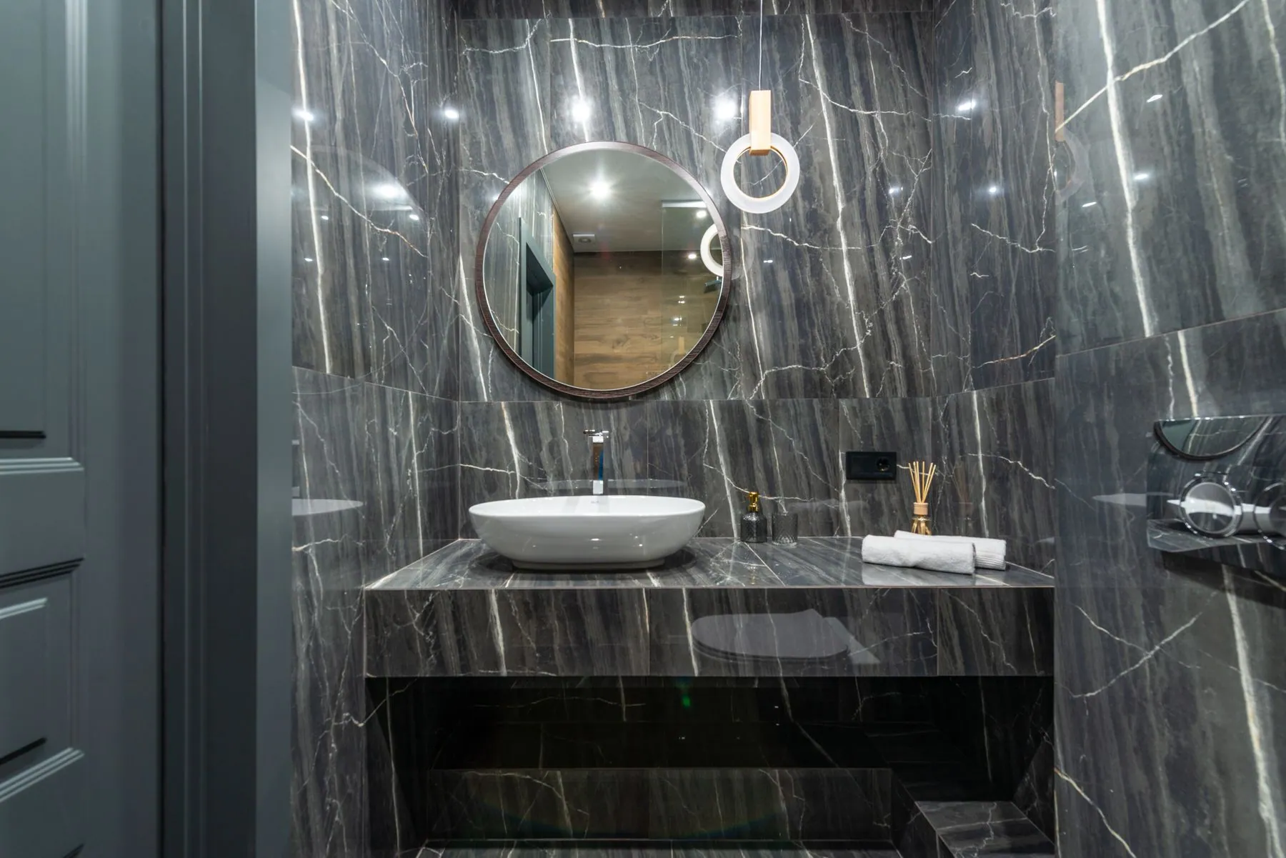 Floating stone vanity shelf with an open recess beneath it, in a powder room lined in veined marble