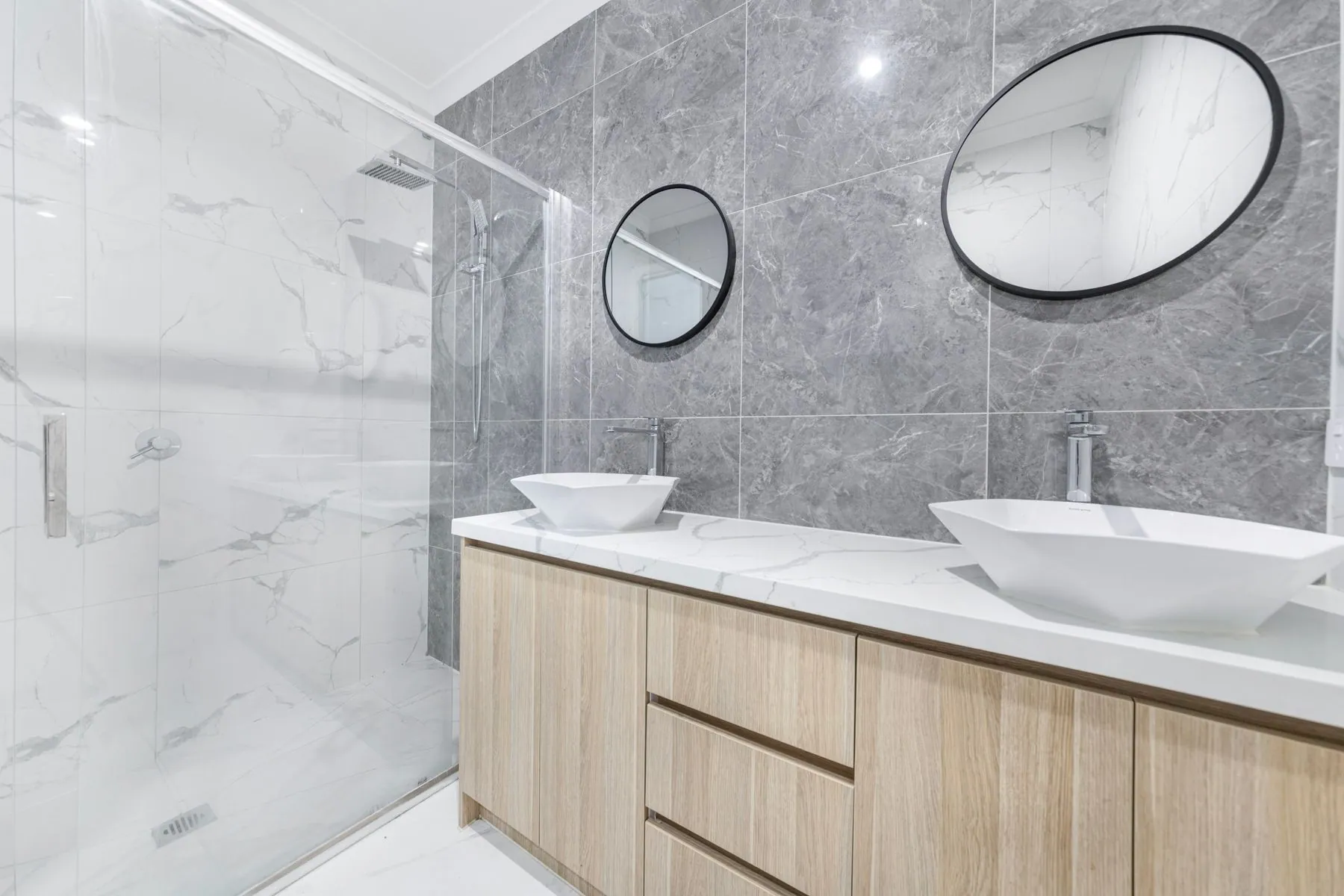 Oak slab-front vanity with a finger-pull edge under a quartz top and two vessel basins