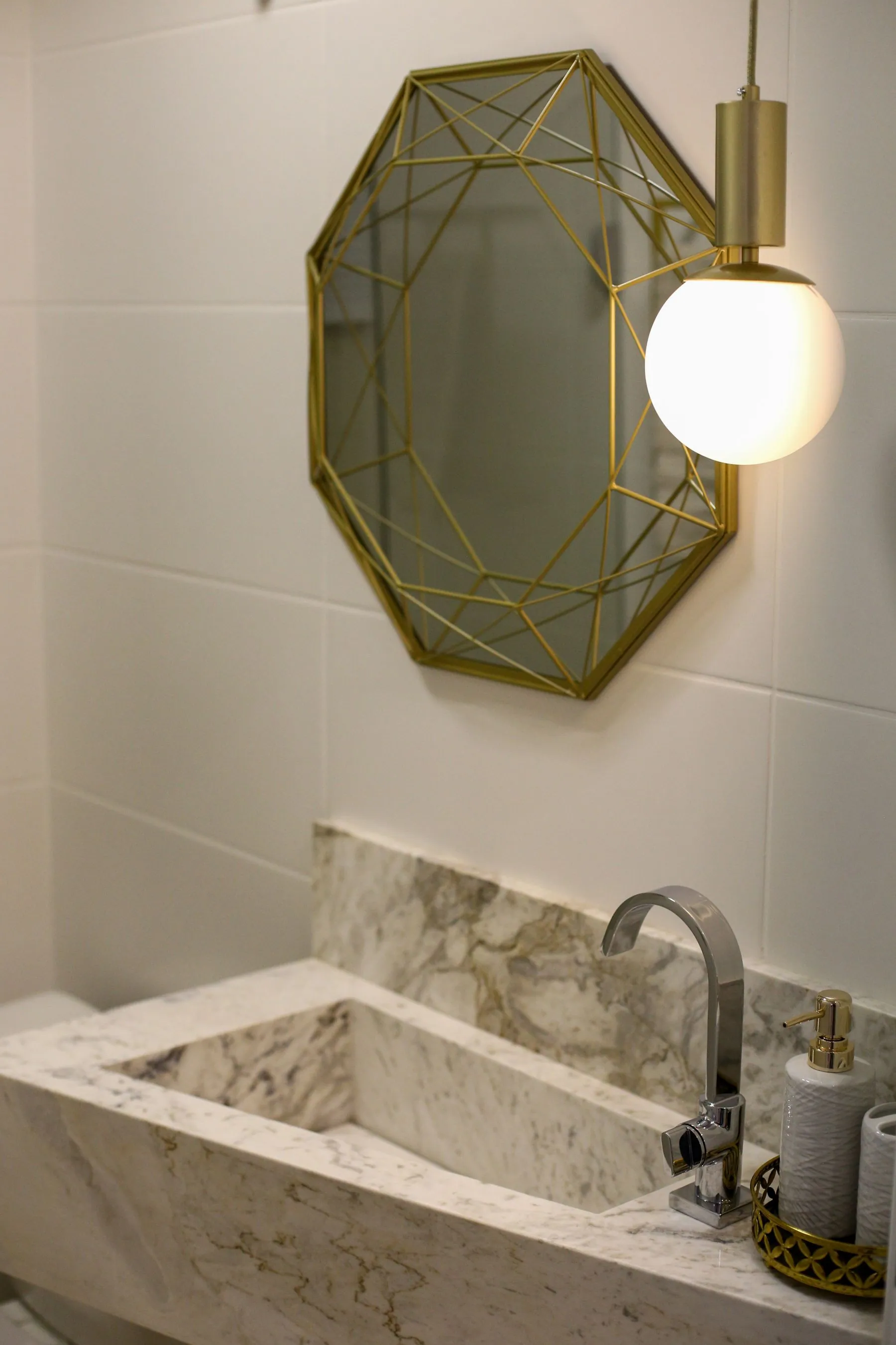 Basin cut directly into a marble slab under a brass-framed mirror in a compact bathroom