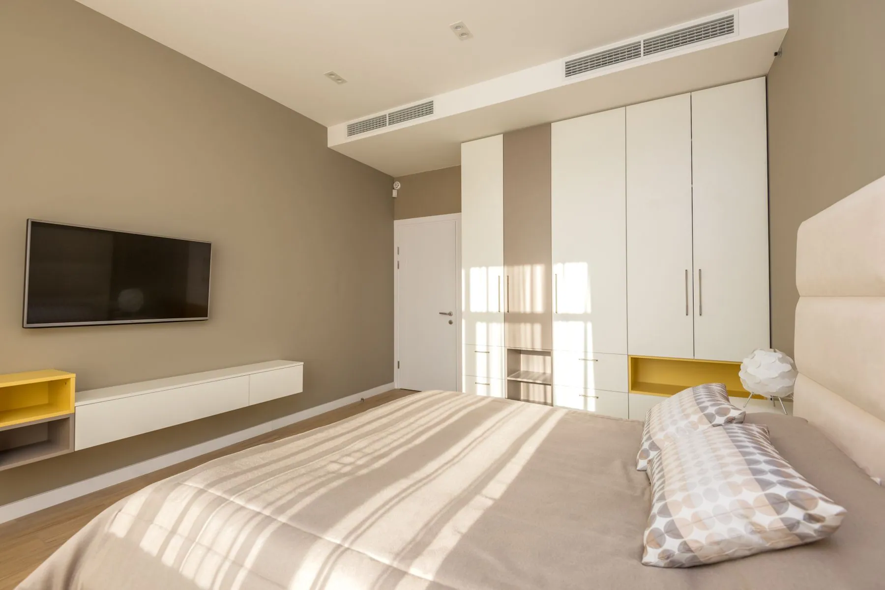 Primary bedroom created from two smaller rooms, with panelled headboard wall and fitted wardrobes