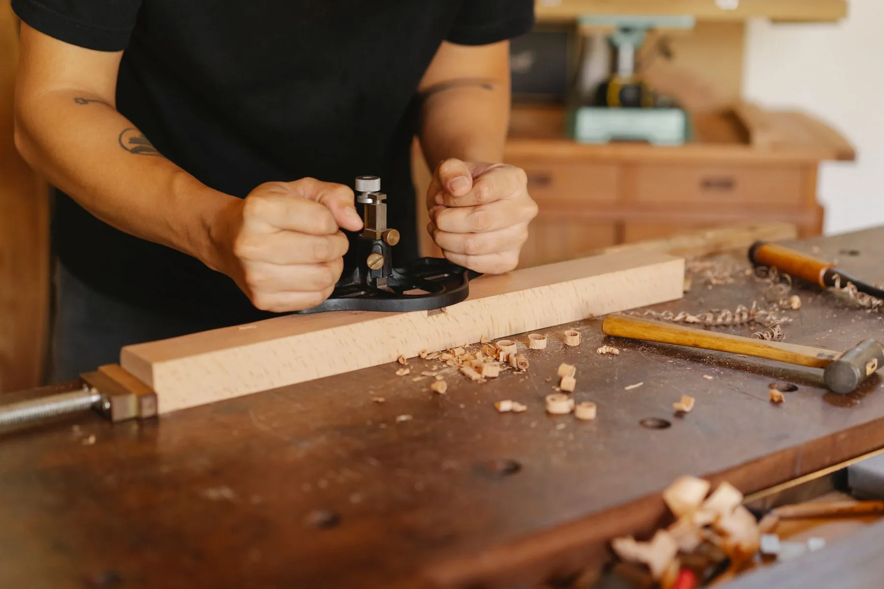 A cabinetmaker easing the edge of a white oak drawer front at the workshop bench