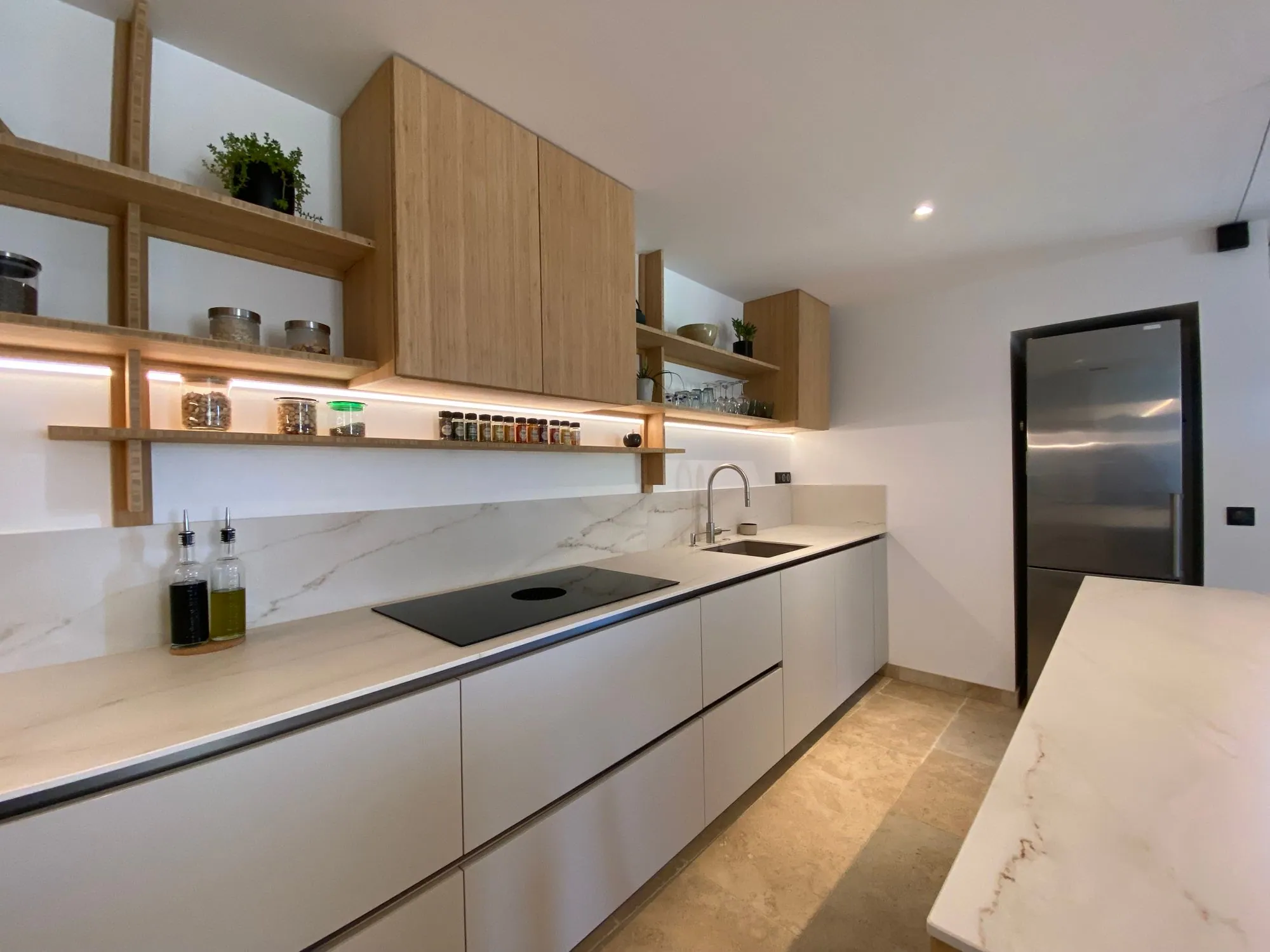 Handleless matte fronts with a dark gola channel between the counter and the drawer bank, under a porcelain splash