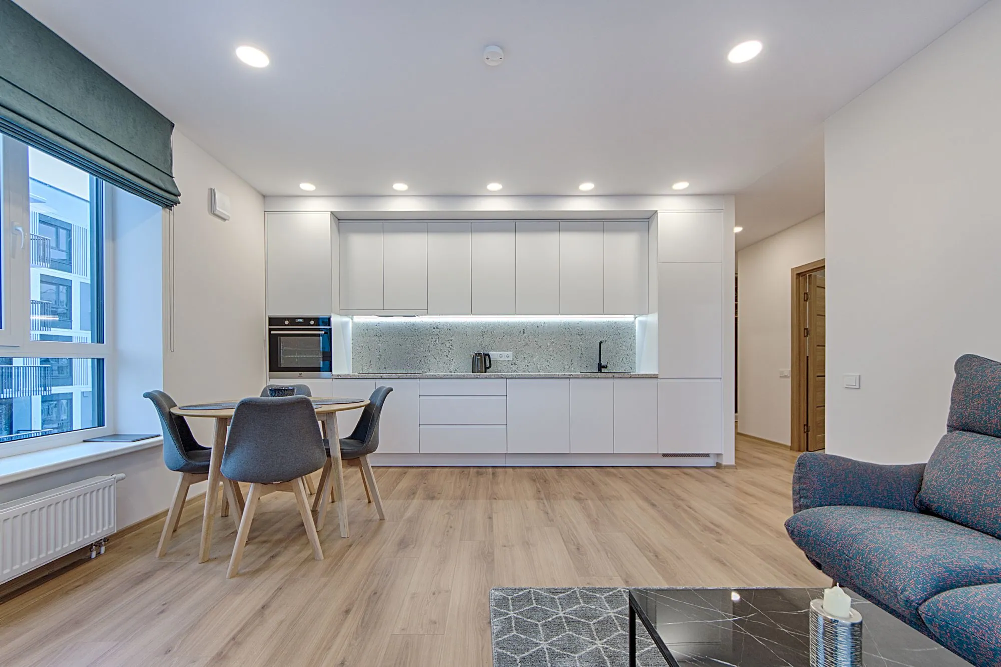 A long handleless run of white cabinetry with drawer banks below and full-height units at one end