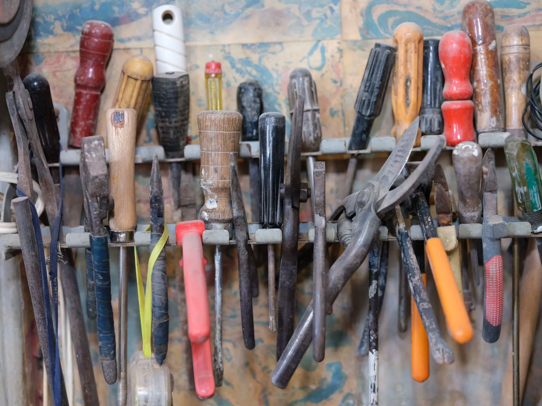 Hand tools racked on a wall bar above a workbench