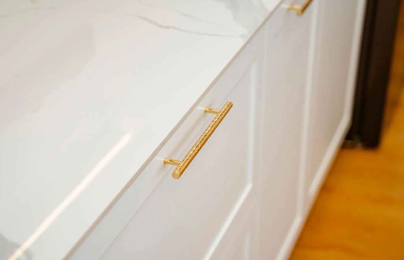 A brushed brass pull mounted on a painted drawer front, seen close