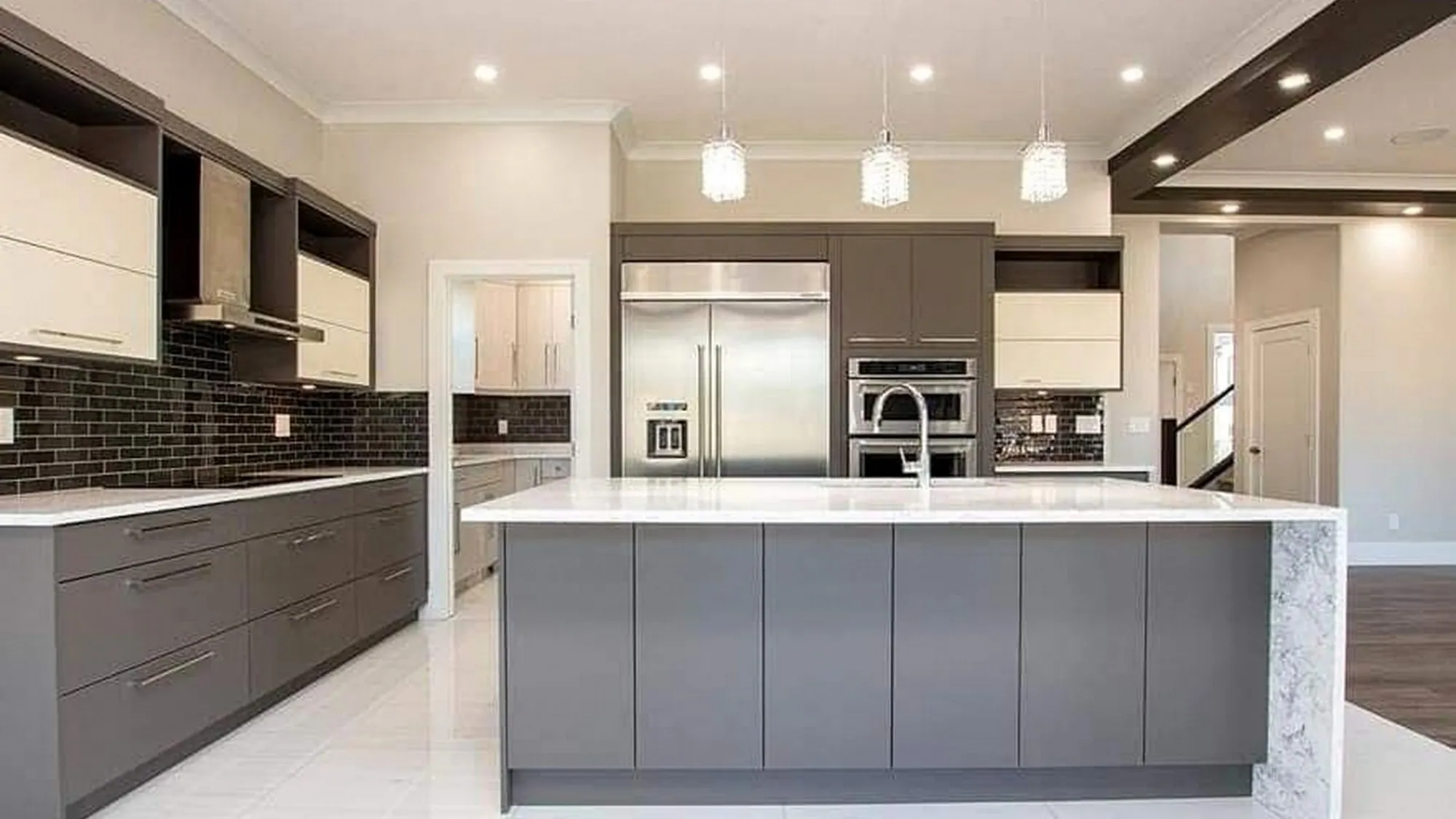 Grey and cream kitchen with a handleless push-to-open island, a marble-look waterfall return and crystal pendants