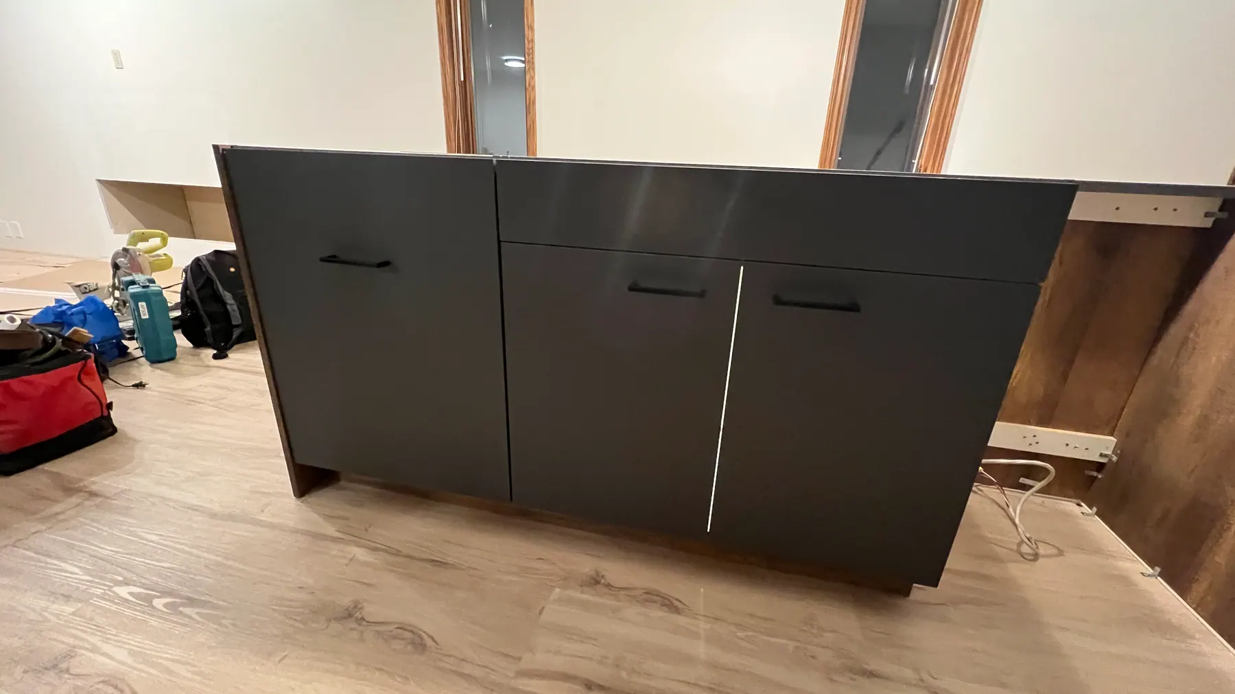 Kitchen run with graphite wall cabinets over a walnut-look base run and quartz counter