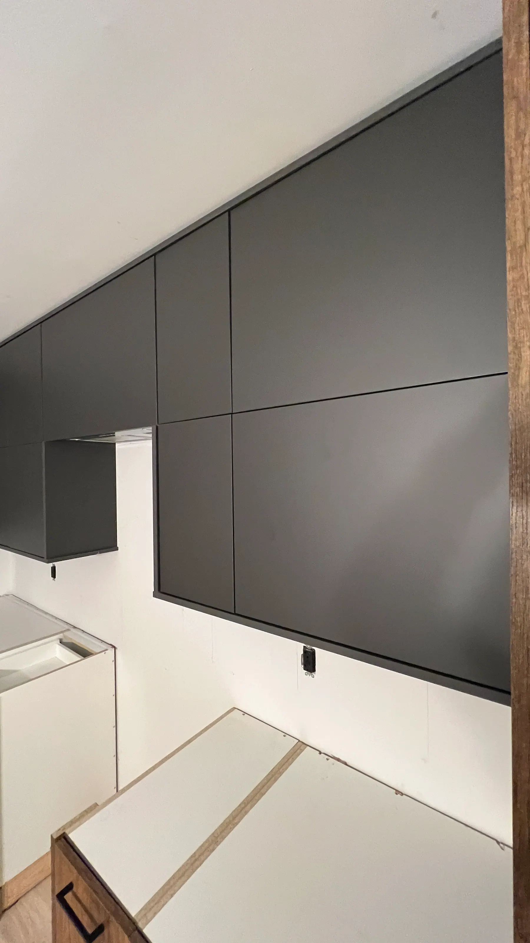 Graphite matte slab fronts meeting the quartz counter, with concealed lighting above