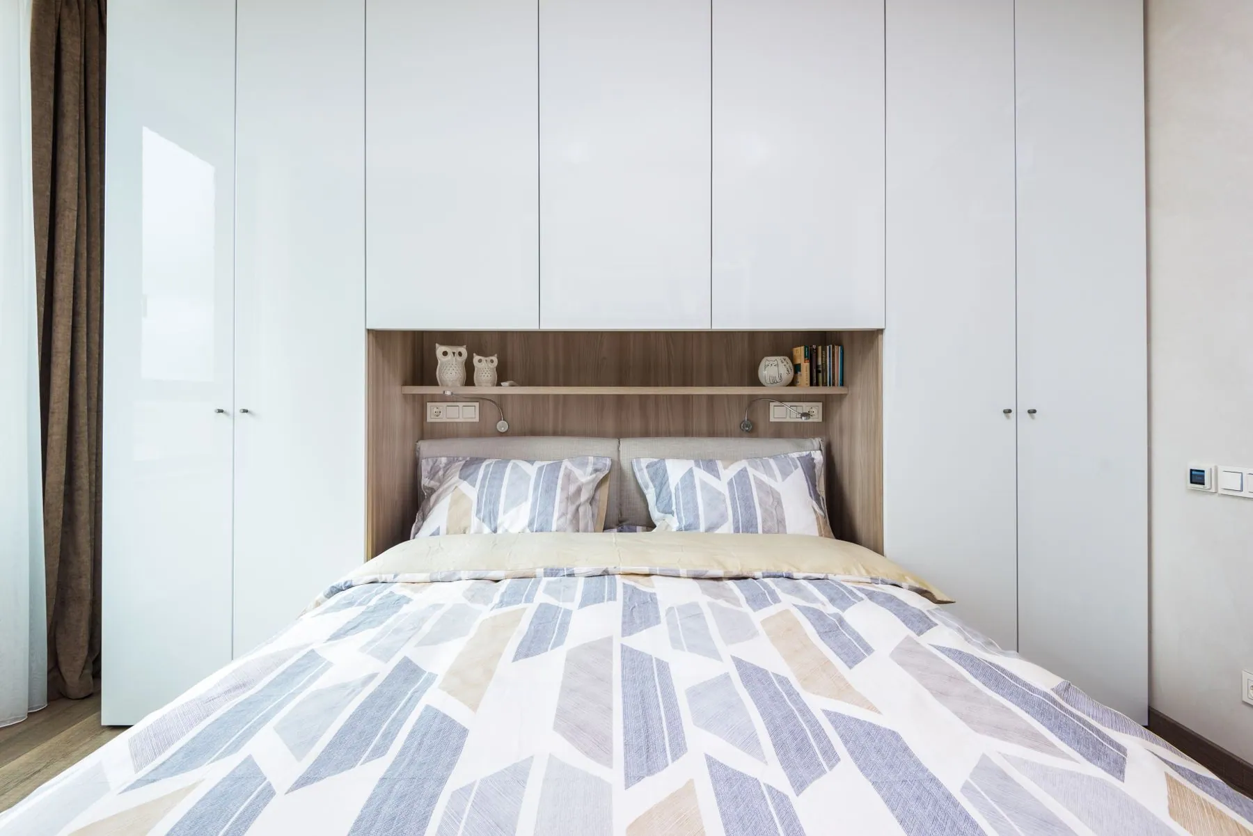 Bedroom wall of handleless wardrobes in super-matte lacquer, scribed to the ceiling with a shadow gap
