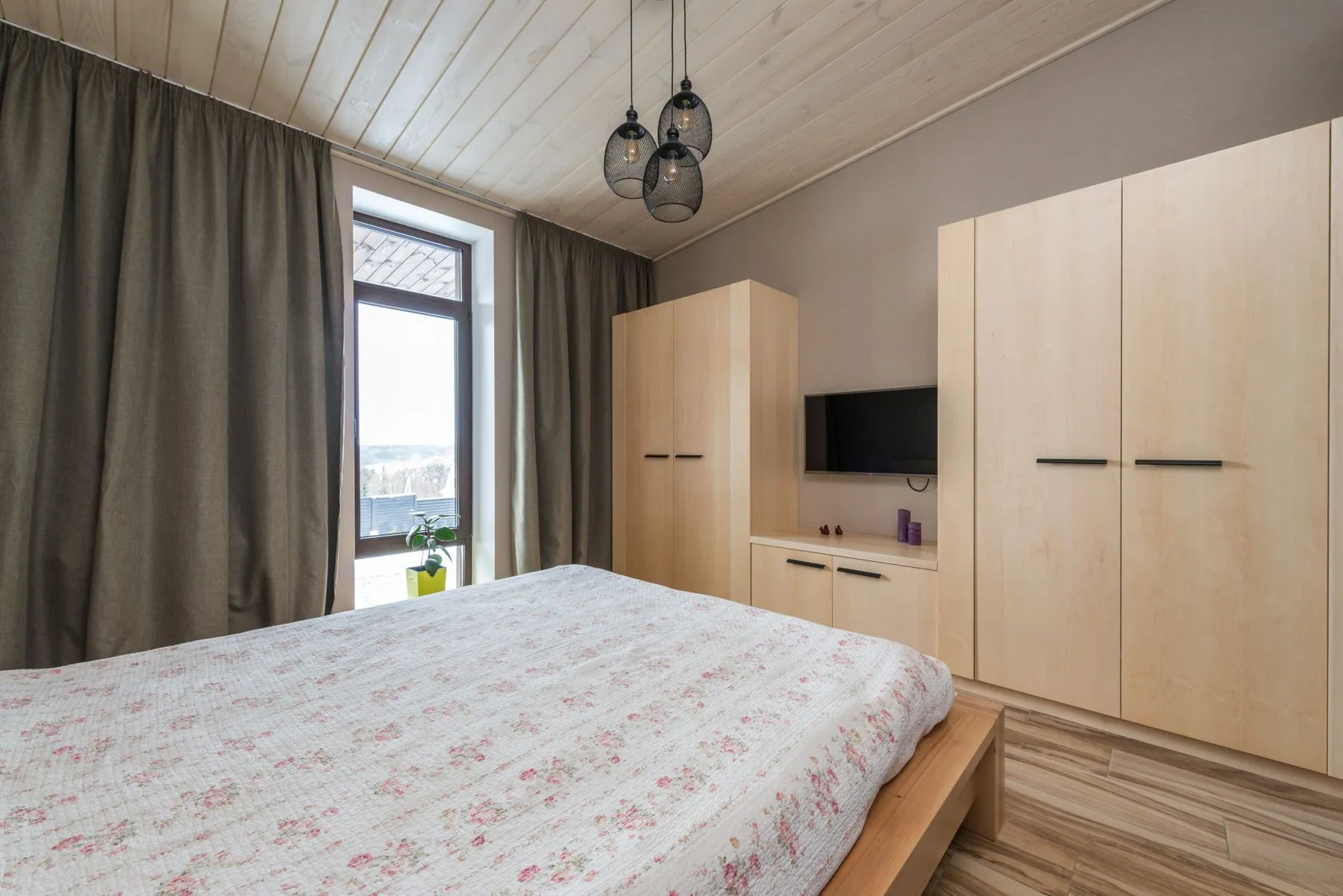 Primary bedroom opening through a wide cased opening into a lit walk-in closet in rift-cut oak