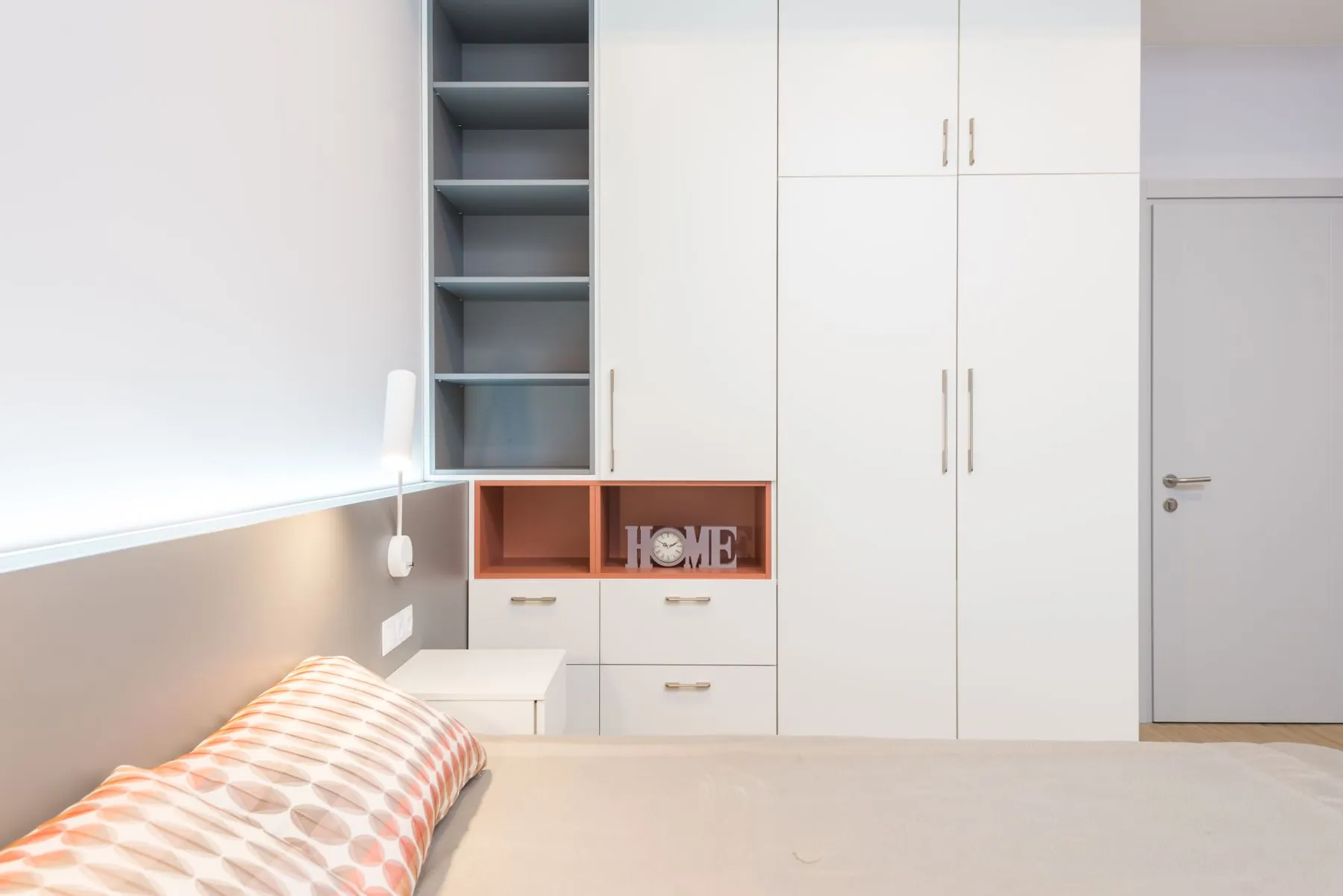 Freestanding wardrobe in book-matched walnut veneer with slim bar pulls and a recessed plinth