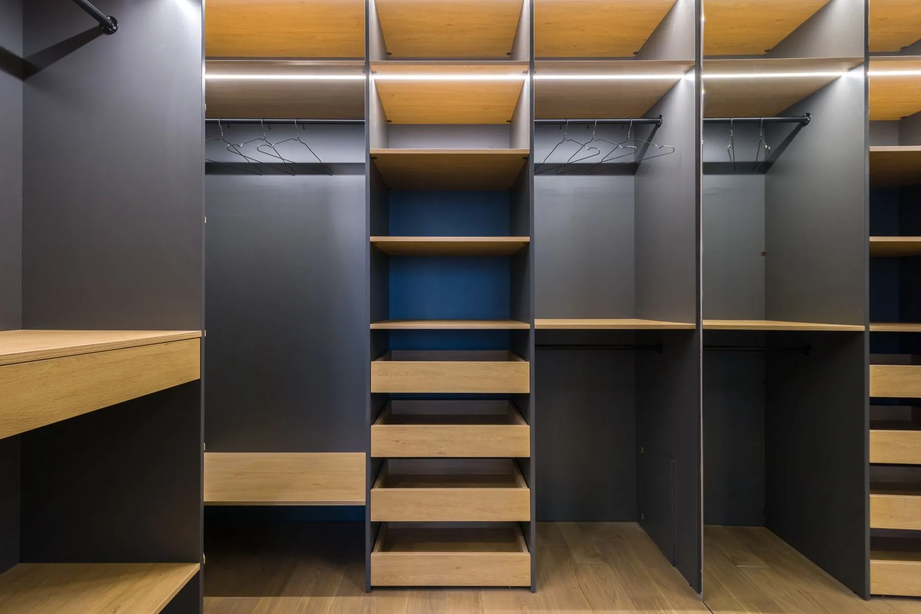 Walk-in closet in rift-cut oak veneer with drawer banks, a gola channel and LED-lit hanging rails