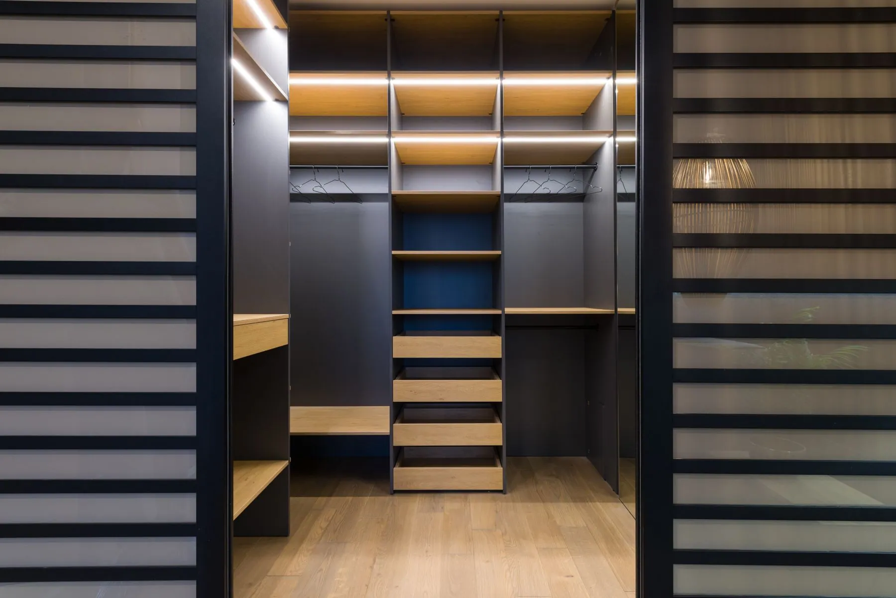 Angled shoe display lit by a recessed LED strip beside open cubbies lined in graphite textured melamine