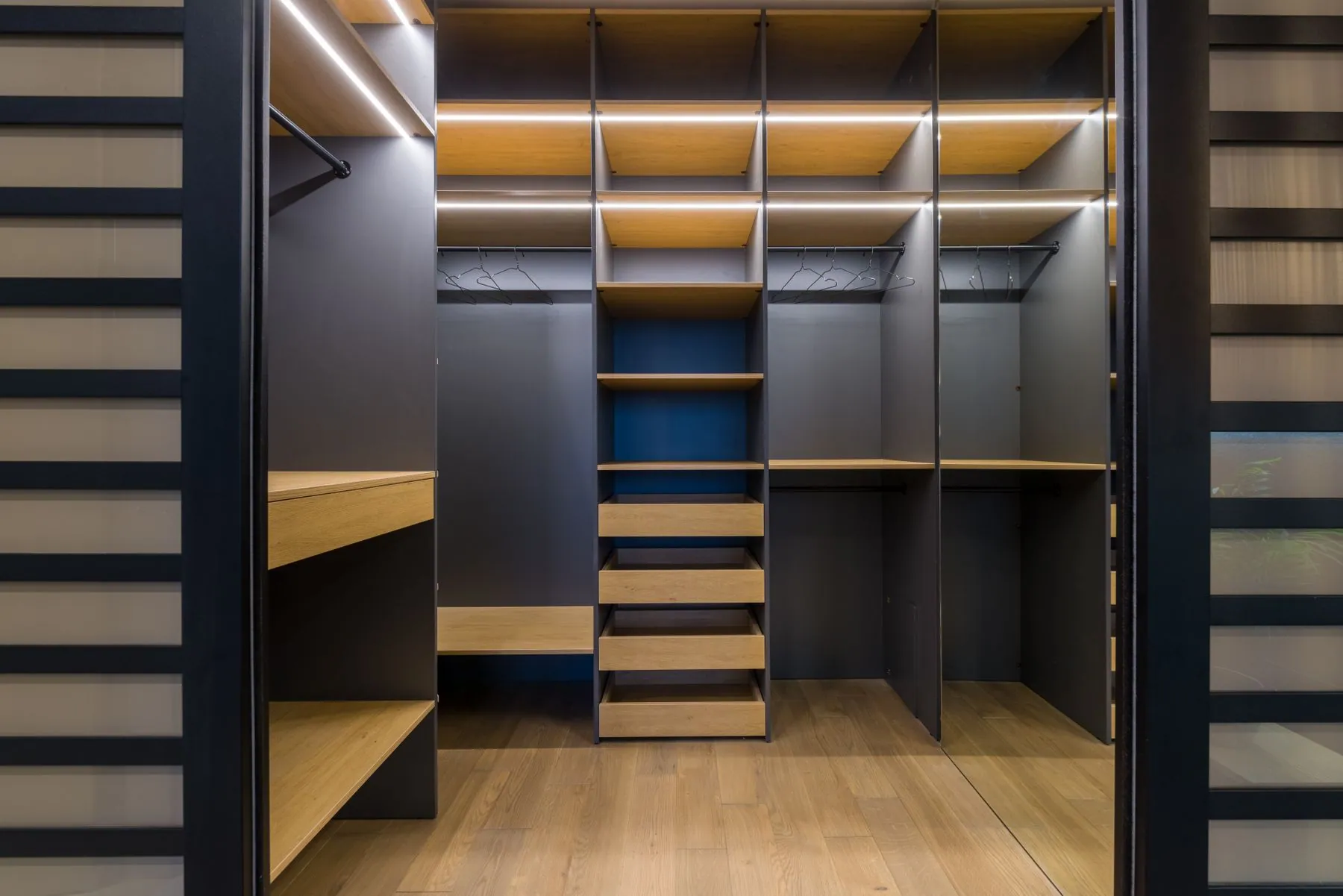 Aluminium-framed glass doors above drawer banks in a dressing room finished in super-matte grey lacquer