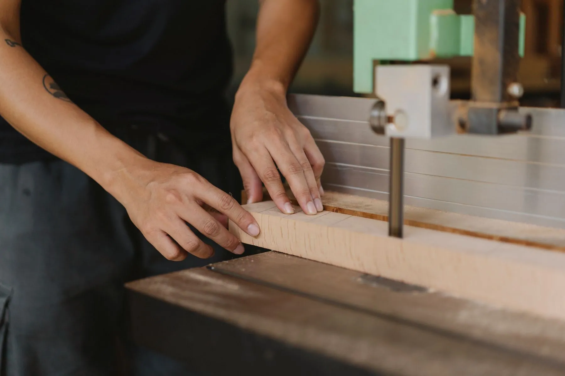 A cabinet maker running a finished panel through the shop, edges taped and labelled