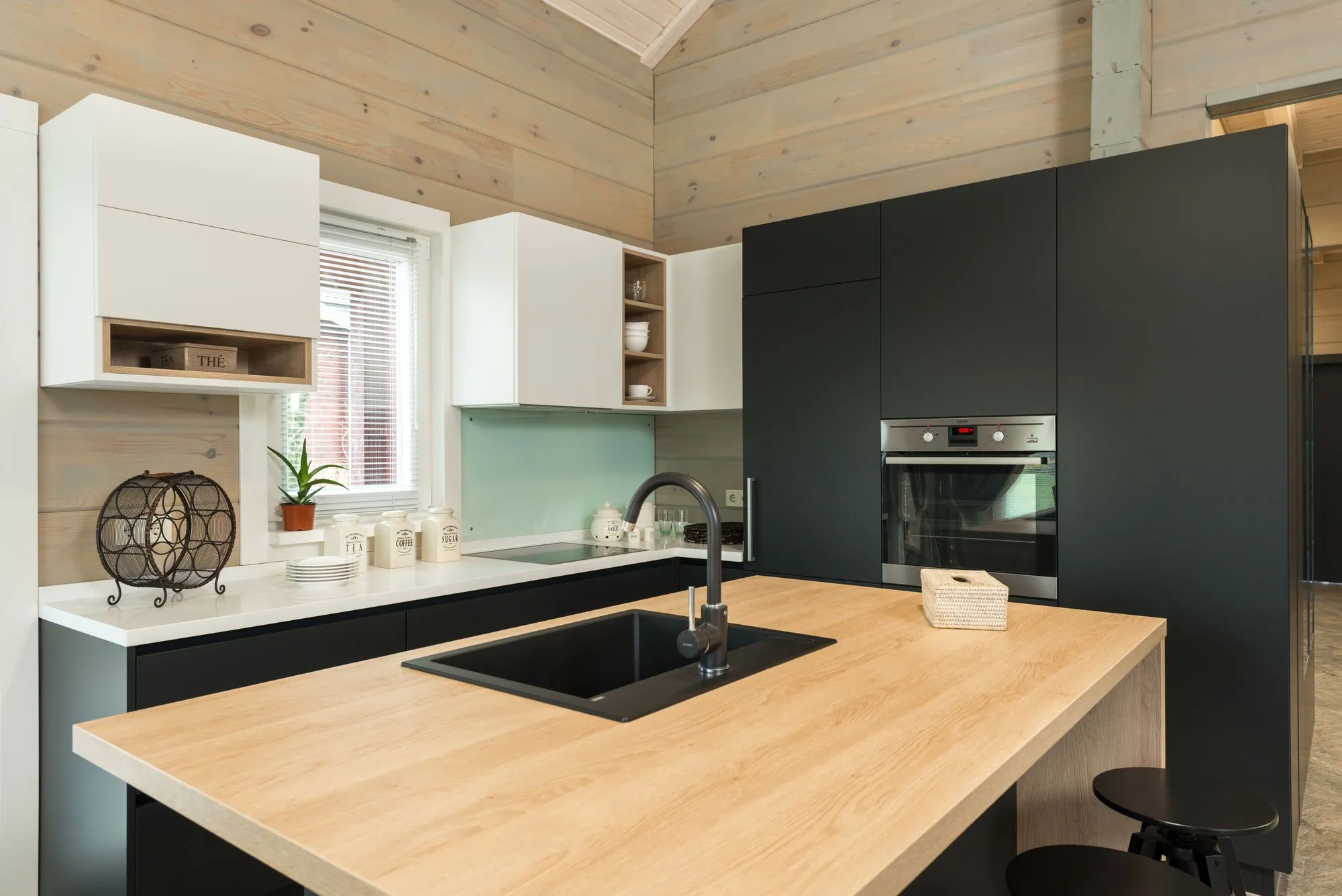 Deep green handleless cabinetry with a solid timber block island under a dark ceiling