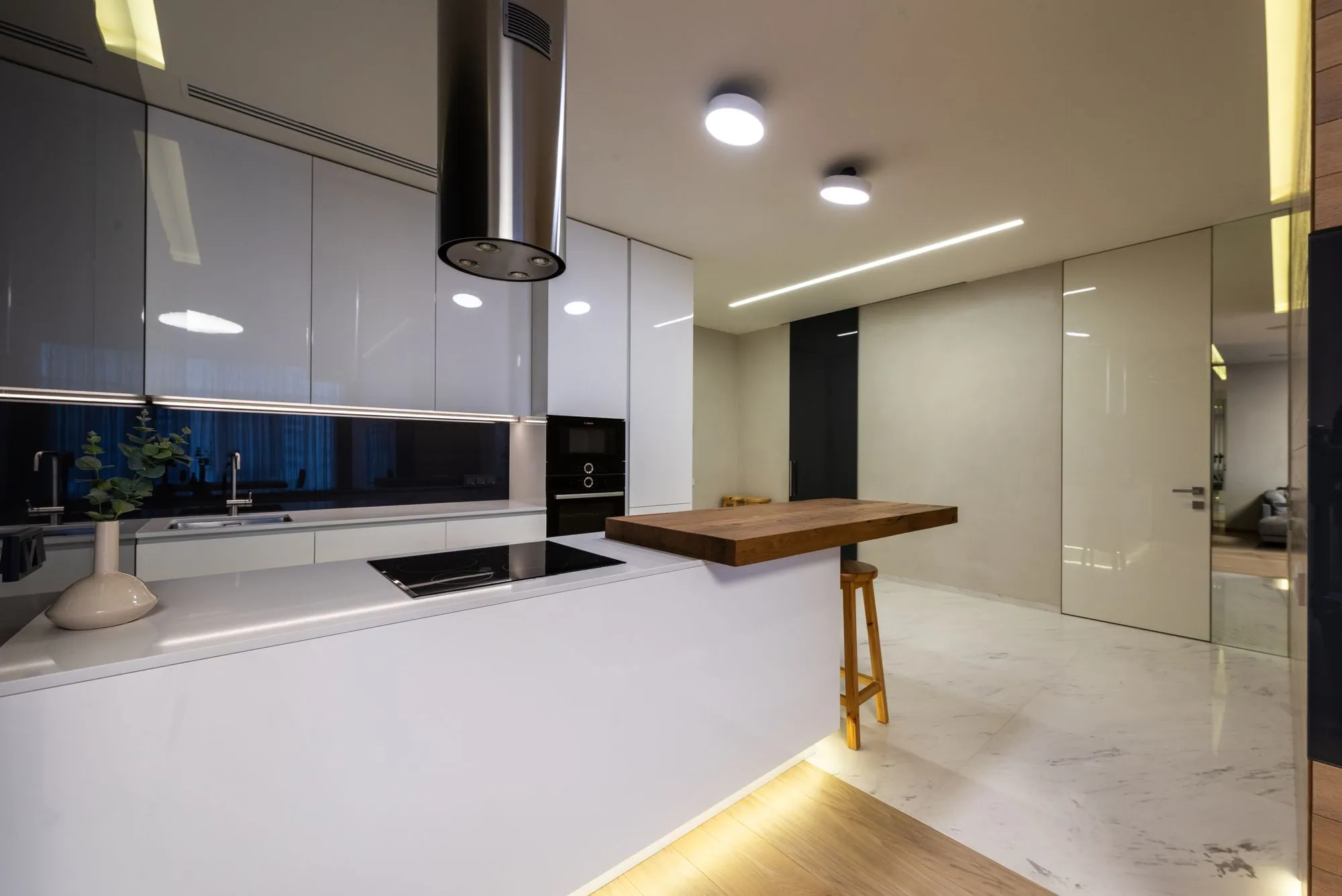 High-gloss white run with a solid oak counter carried off the end as a standing bar