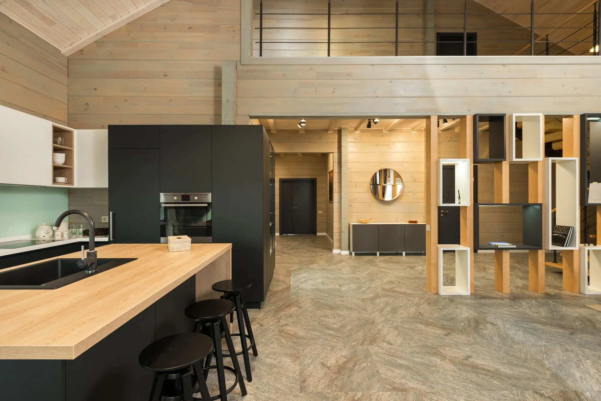 Dark slab cabinetry meeting a timber ceiling, with a sculptural island under concealed lighting