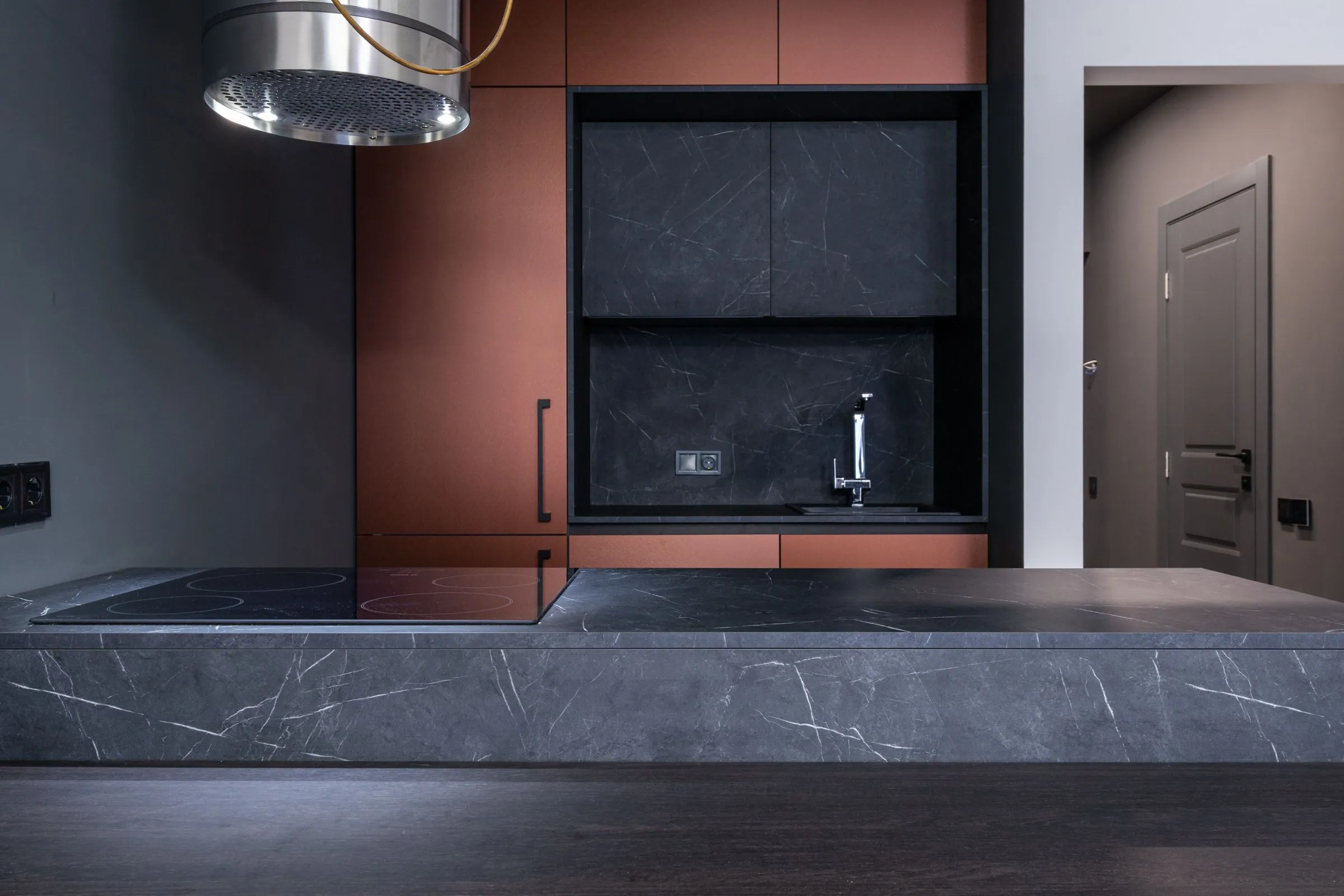 Matte dark cabinetry and a honed stone counter lit from a single window