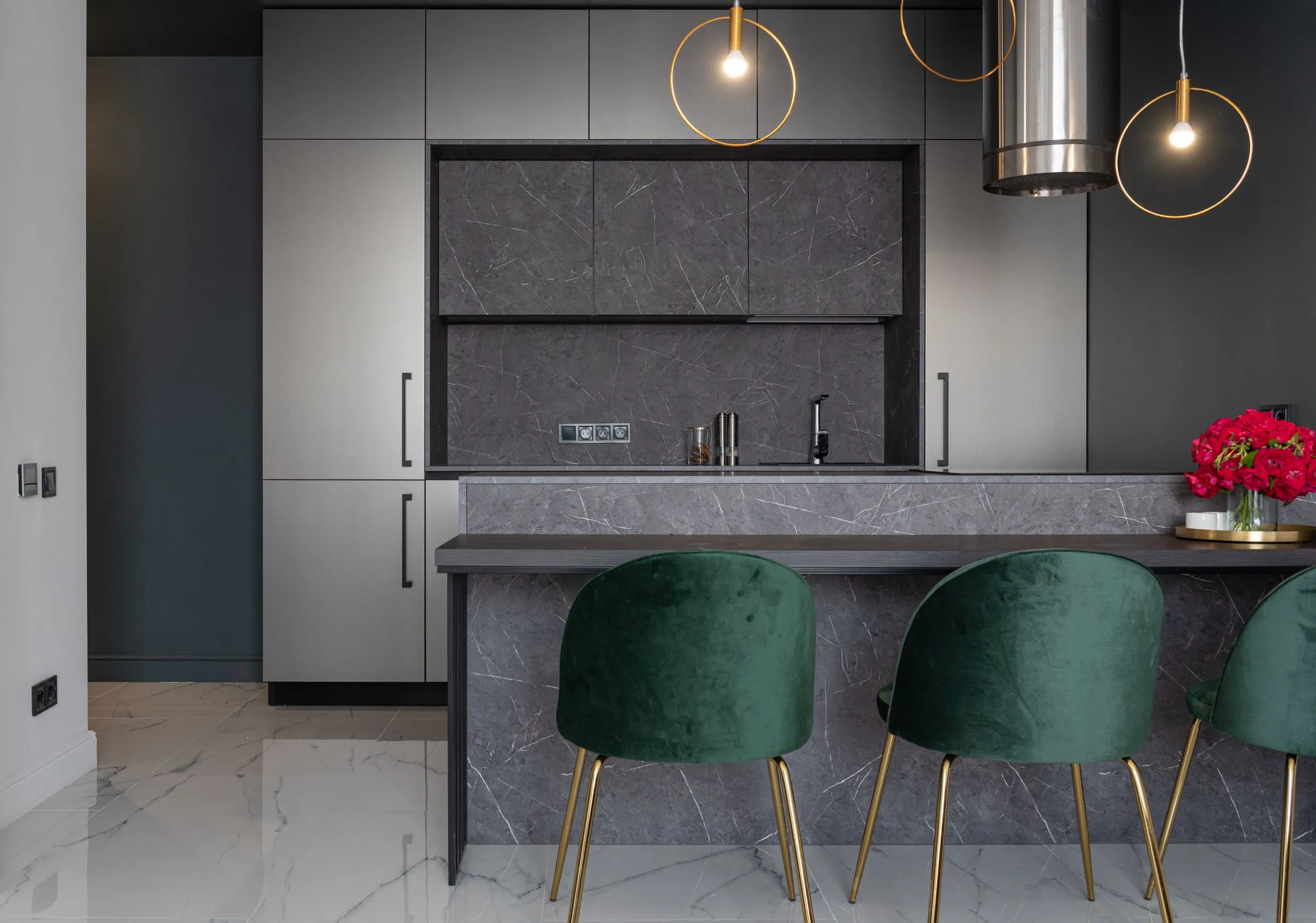 A wide kitchen with pale oak cabinetry, a honed stone island and matte black hardware