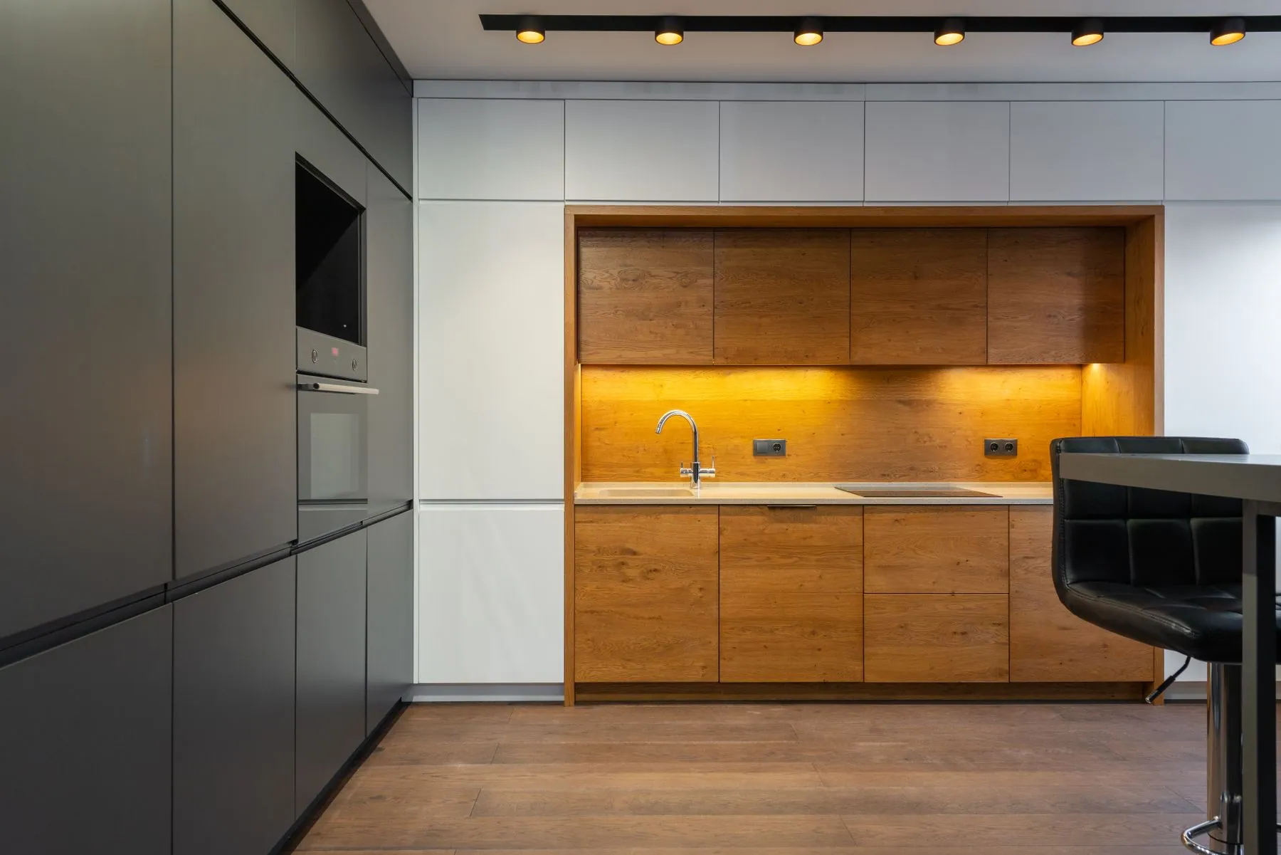 A pale minimal kitchen with an oak niche lit from above