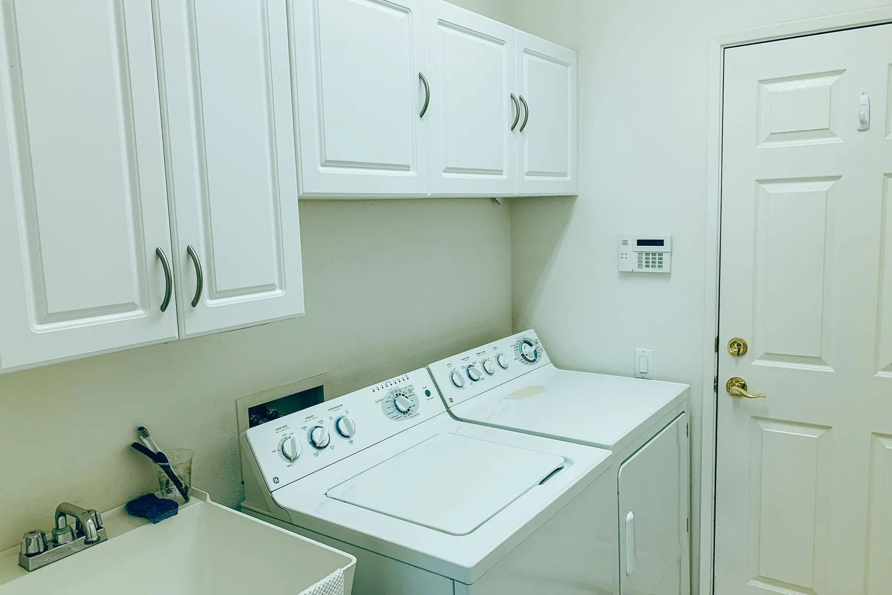 Laundry room with wall cabinets above the machines and a utility sink at the end of the counter run