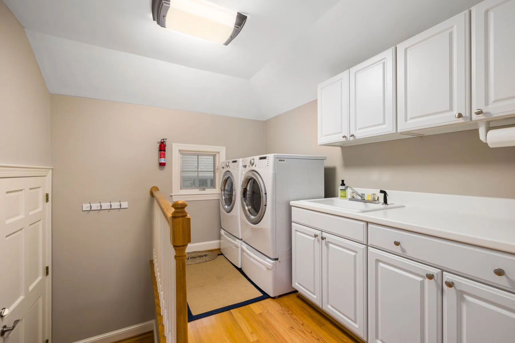 Upper cabinets over a folding counter, with front-loading machines and a utility basin at the end of the run