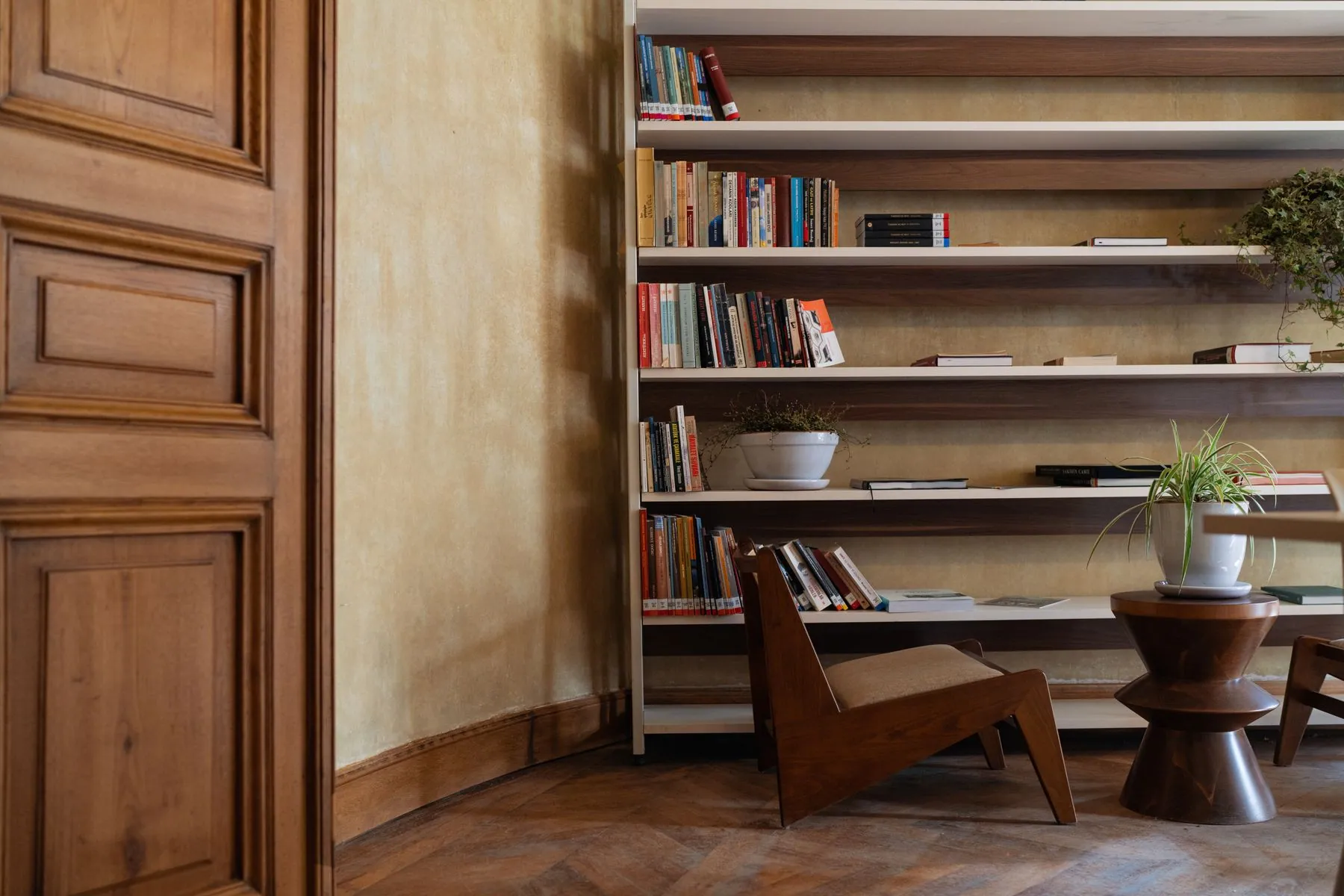 Walnut library shelving built around a reading chair, lit from the shelf edges