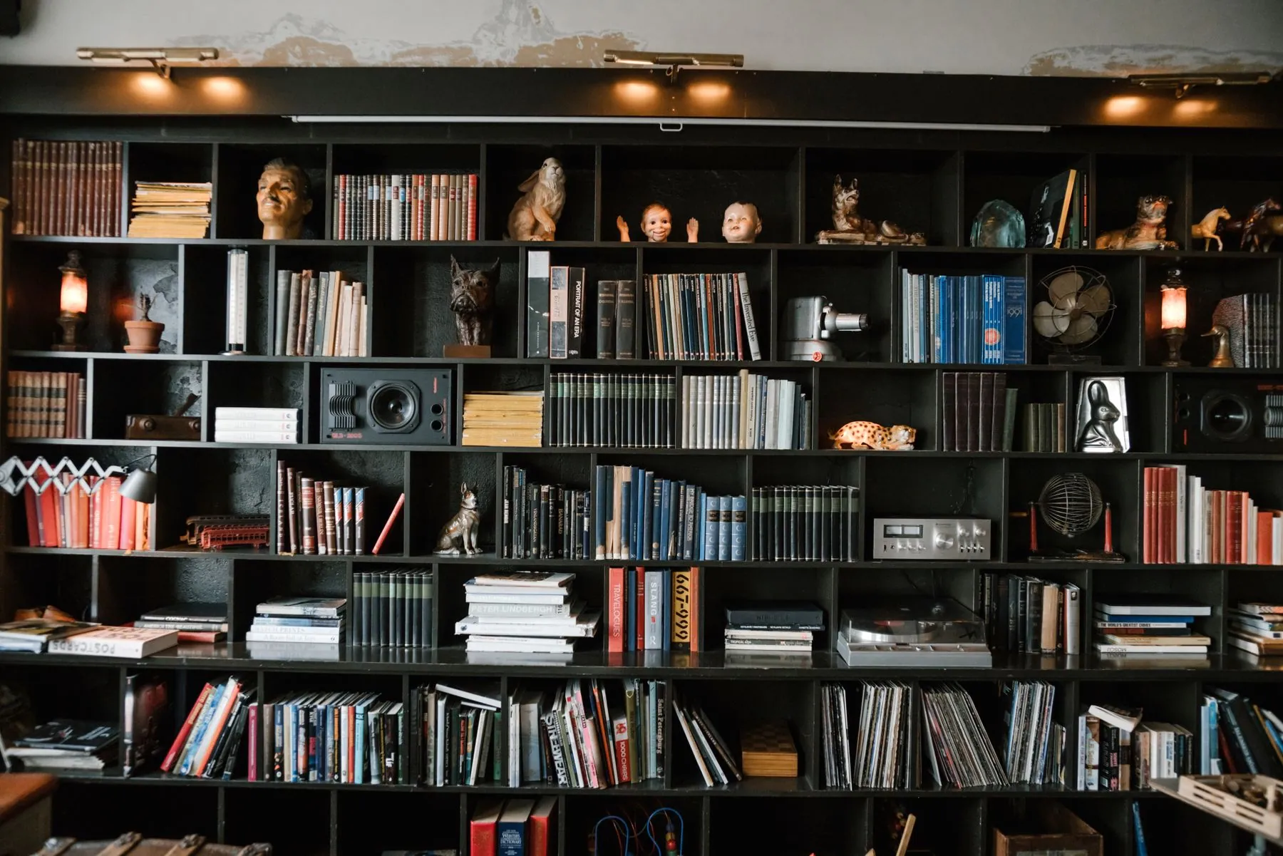 Open shelving beside a screen wall holding books and consoles above push-to-open drawers