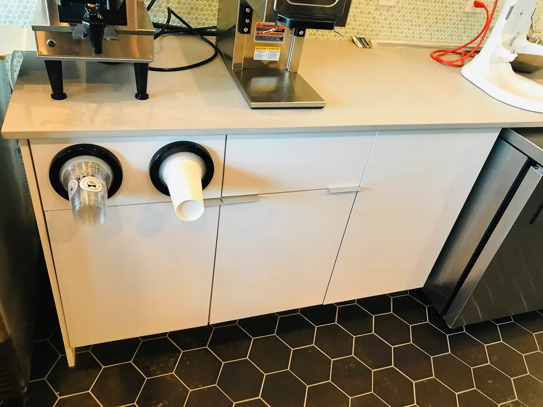 Cup dispenser counter in white slab, cut to take the equipment