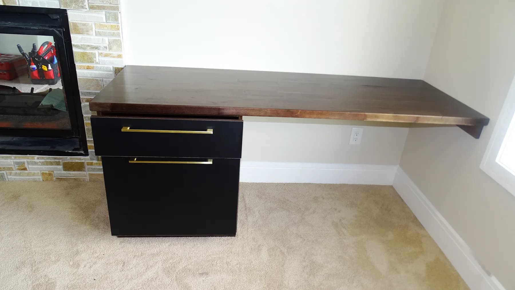 The desk run seen in full, carried along the wall beside a stone fireplace