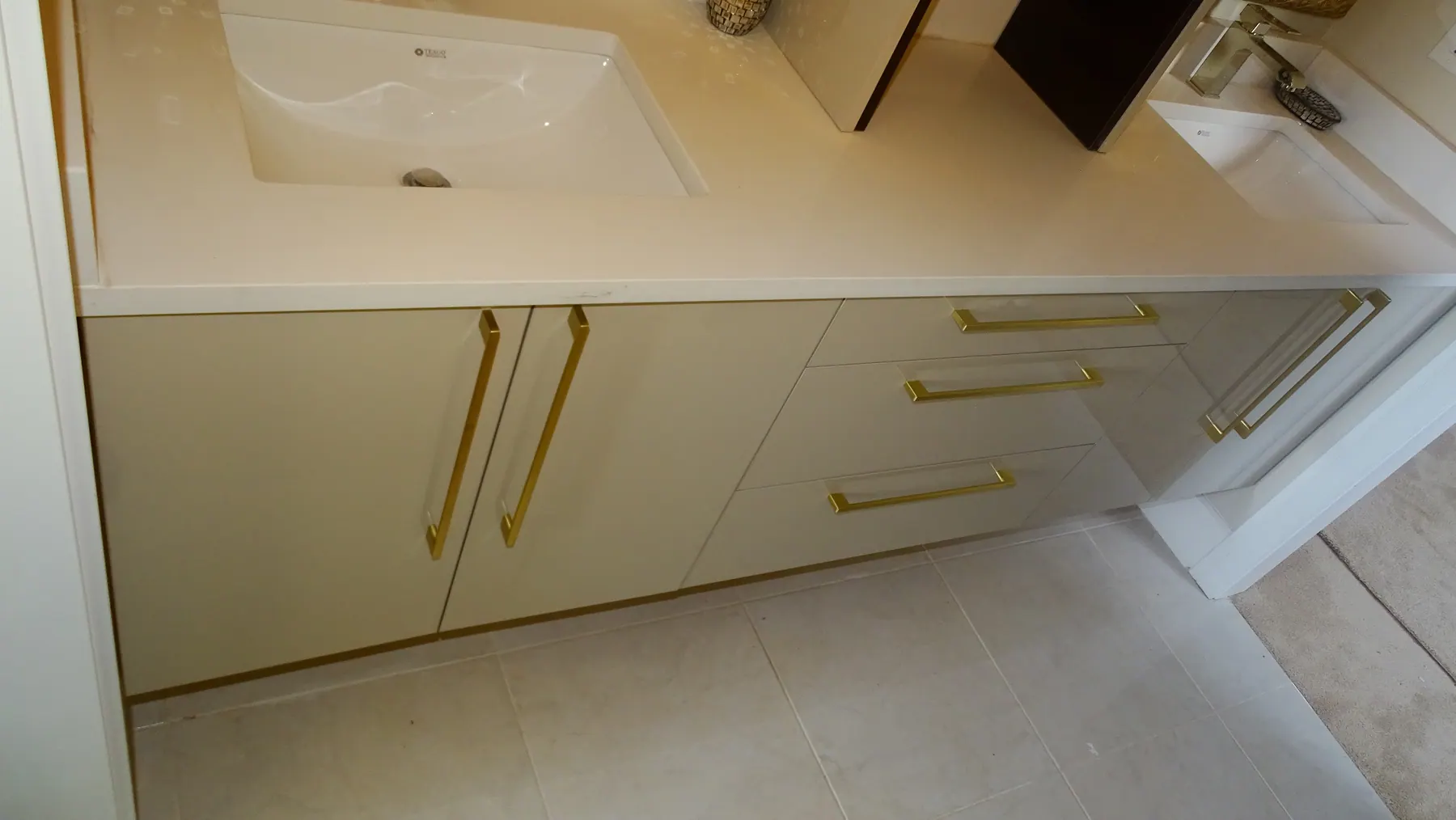Gloss vanity in cream with brass pulls and an inset basin