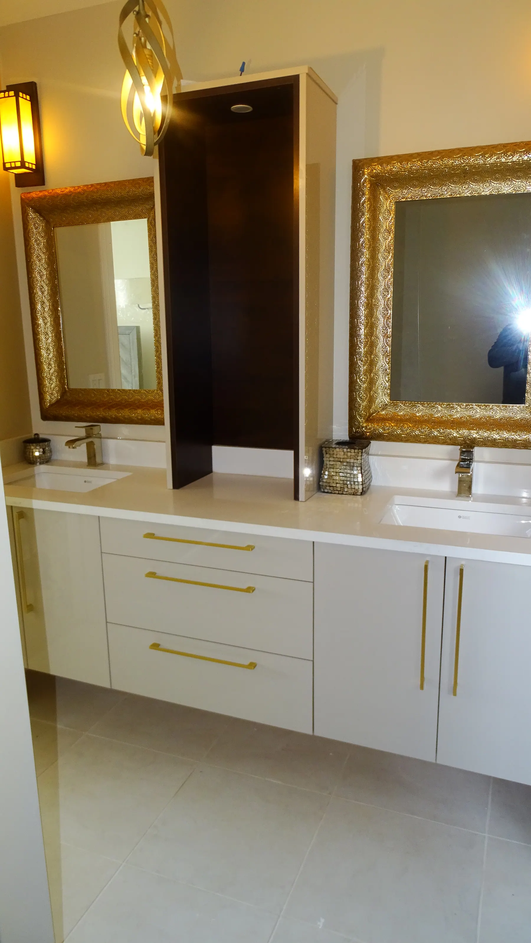 Twin vanity with brass pulls, undermount basins and gold-framed mirrors