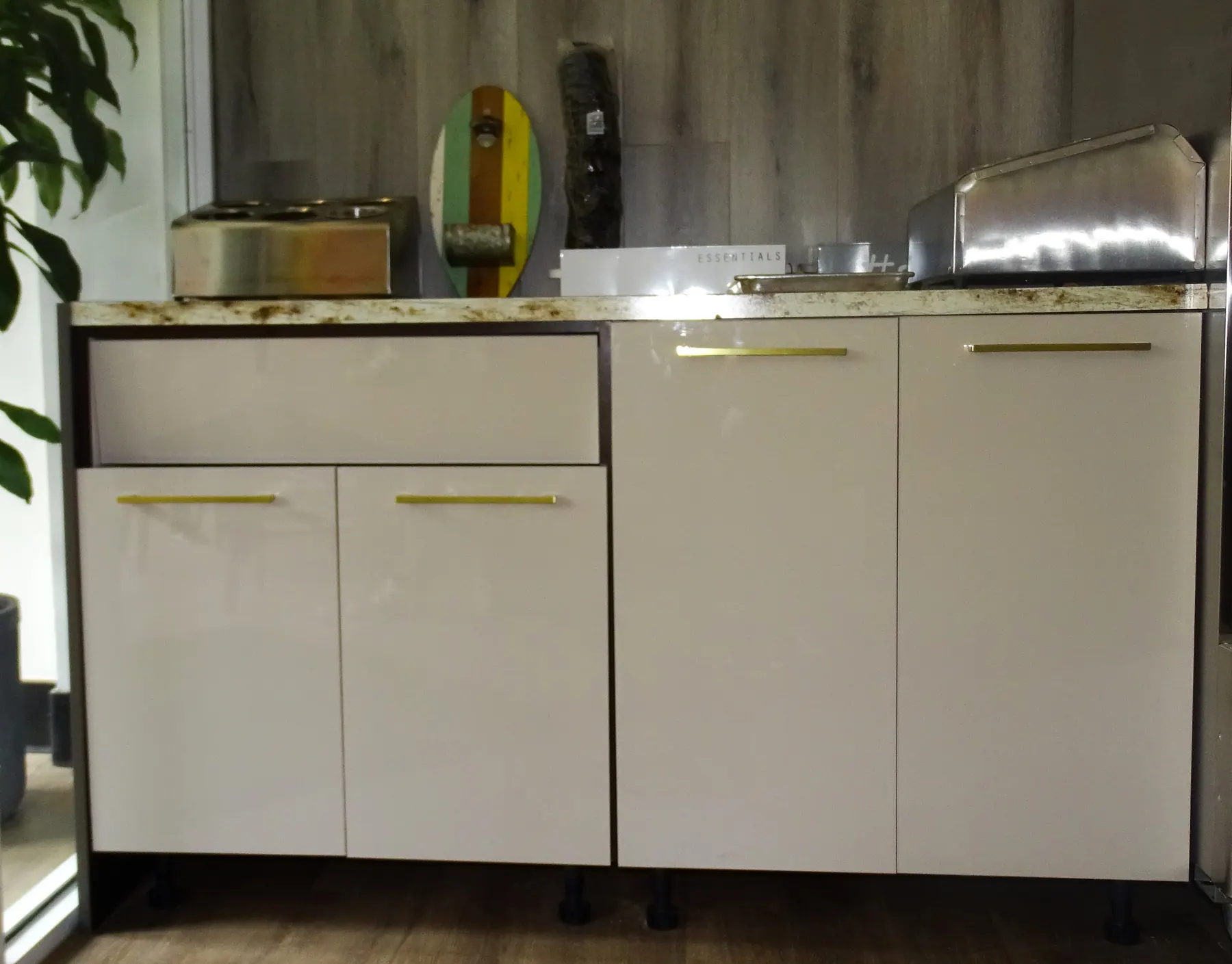 White gloss slab cabinetry on brass pulls under a granite counter
