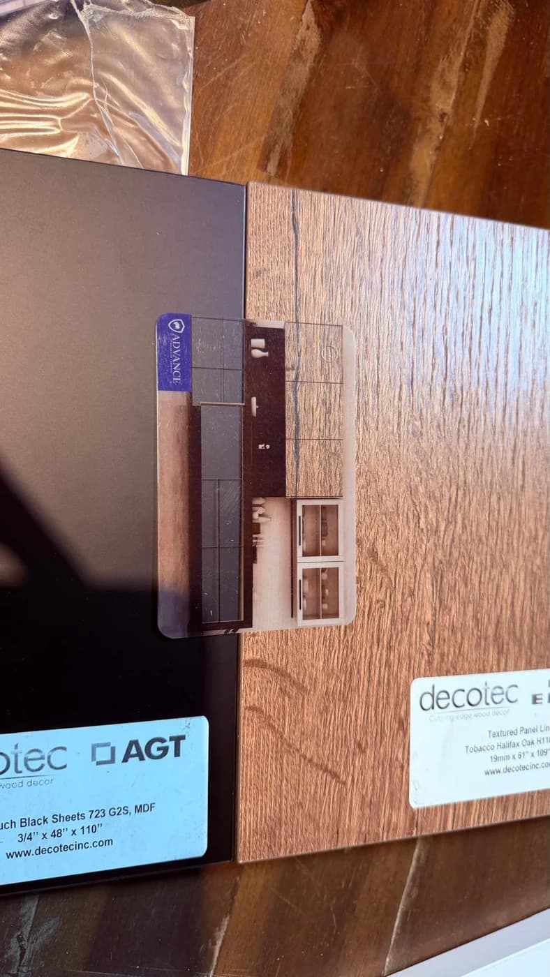 Two panel boards side by side, labelled AGT Soft Touch Black 723 and Egger Tobacco Halifax Oak